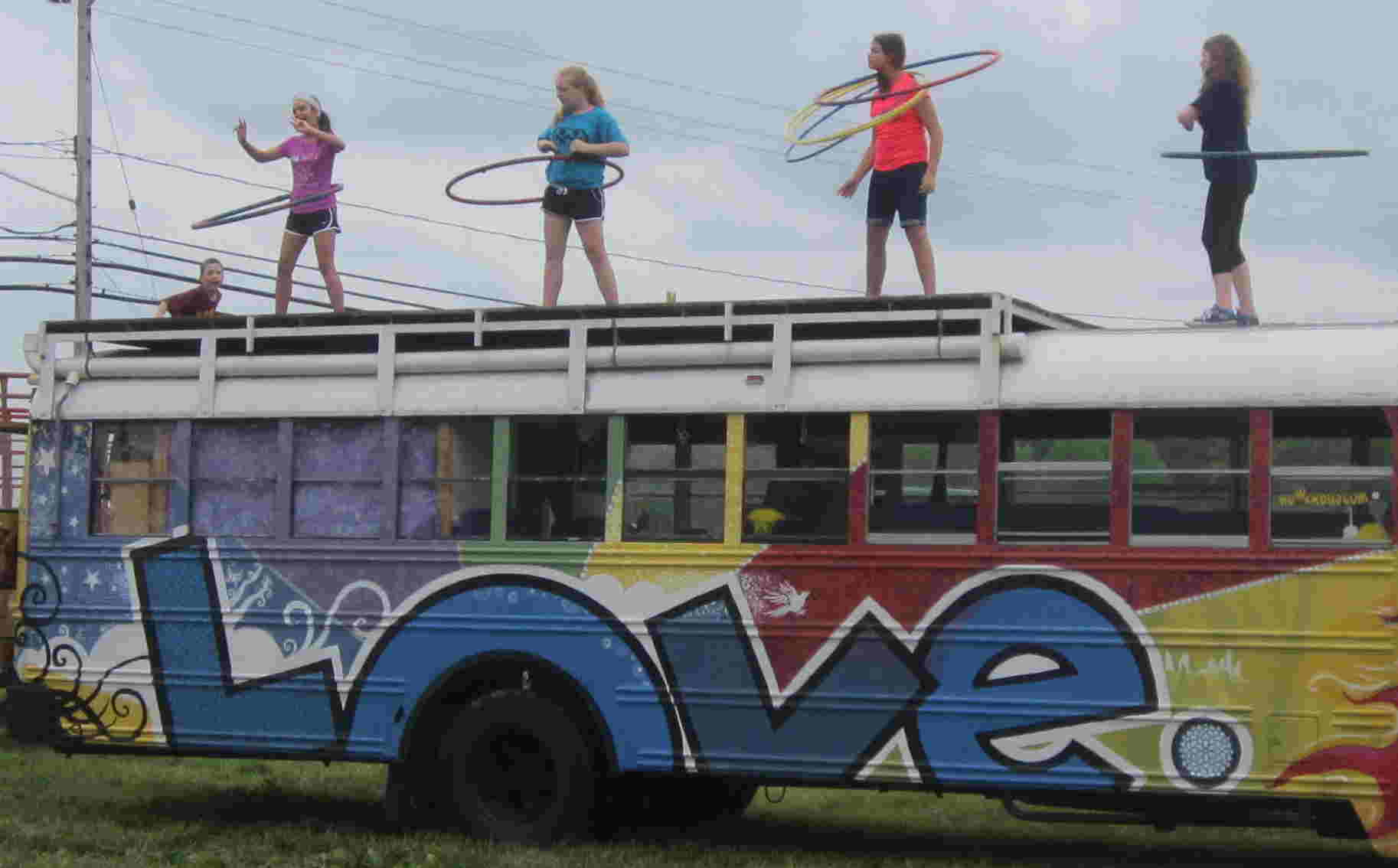 4 kids with hula hoops on top of a bus painted with a Love motif